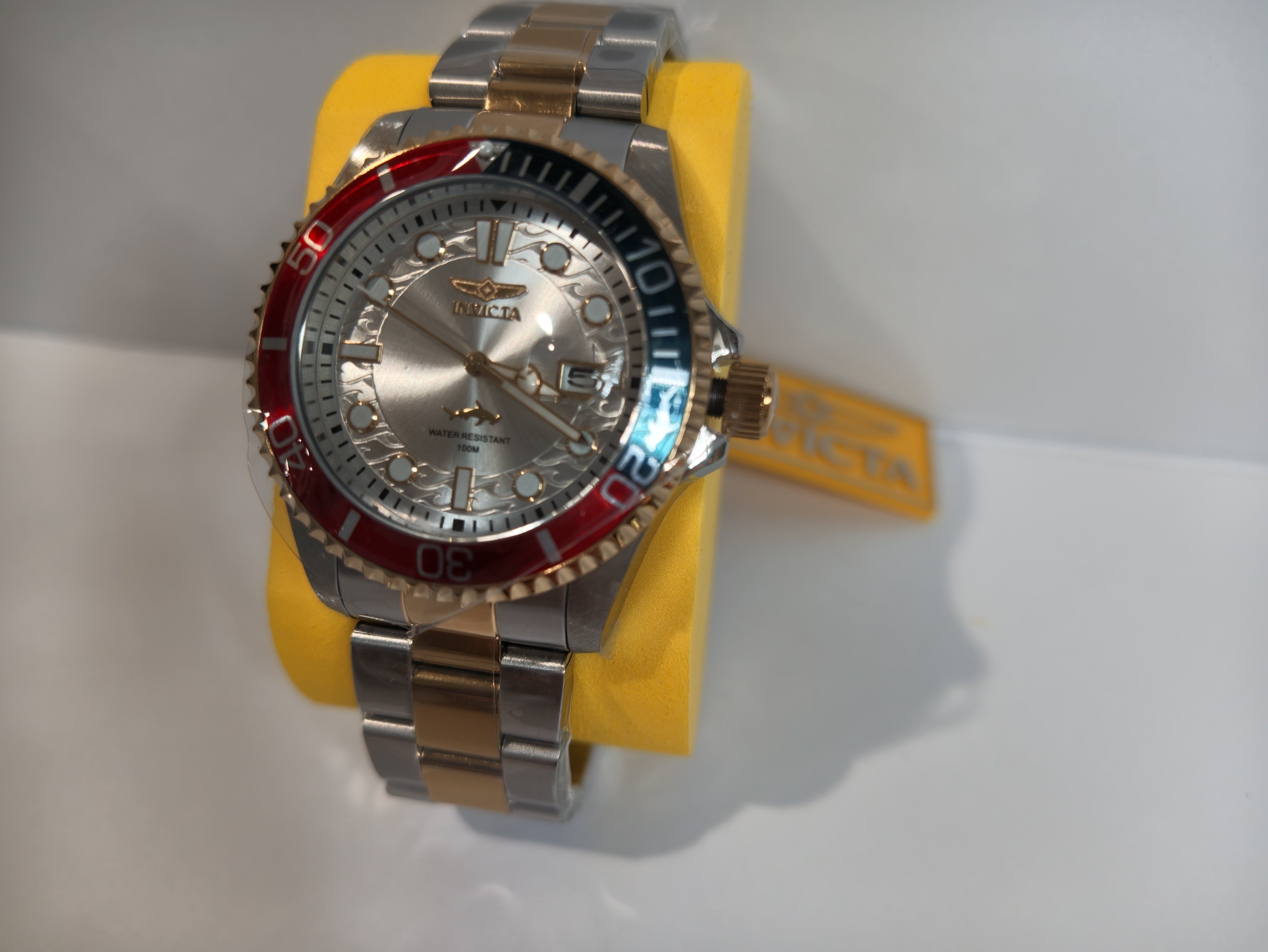 Invicta two-tone rose gold watch angled view showing wave dial and shark logo
