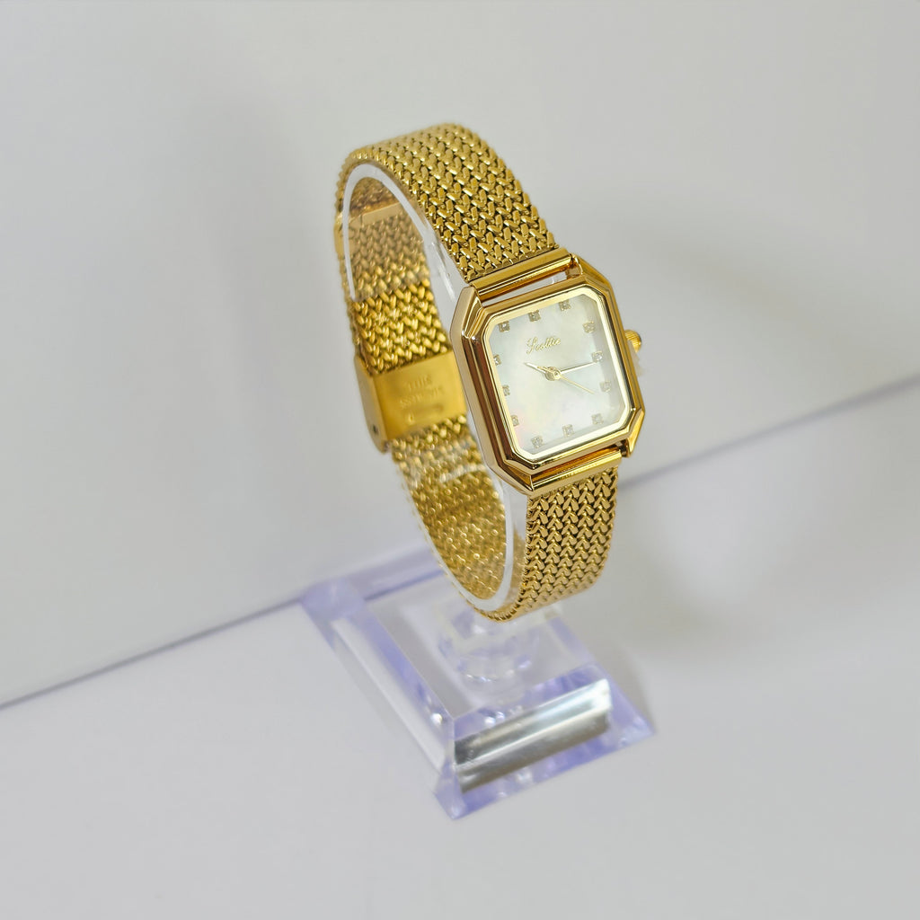 Womens gold mesh bracelet watch with square white dial and crystal markers on wrist
