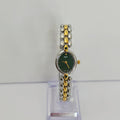 A women's two-tone watch with a dark green dial and a silver and gold beaded link bracelet, displayed on a clear stand against a light gray background.