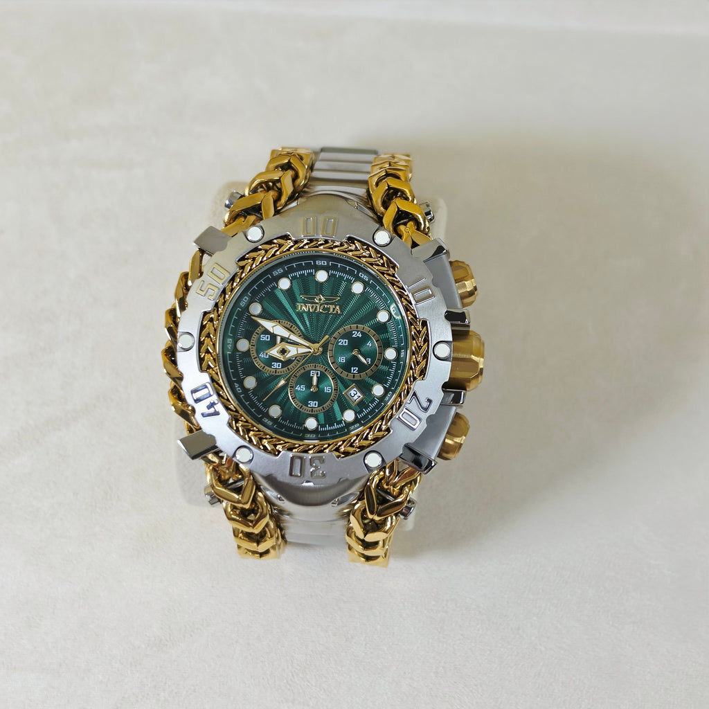 A luxury wristwatch by Invicta, featuring a green sunburst dial, a silver-tone bezel with Roman numerals, and a distinctive gold-tone chain-link bracelet, displayed on a light beige background.