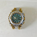 A luxury wristwatch by Invicta, featuring a green sunburst dial, a silver-tone bezel with Roman numerals, and a distinctive gold-tone chain-link bracelet, displayed on a light beige background.