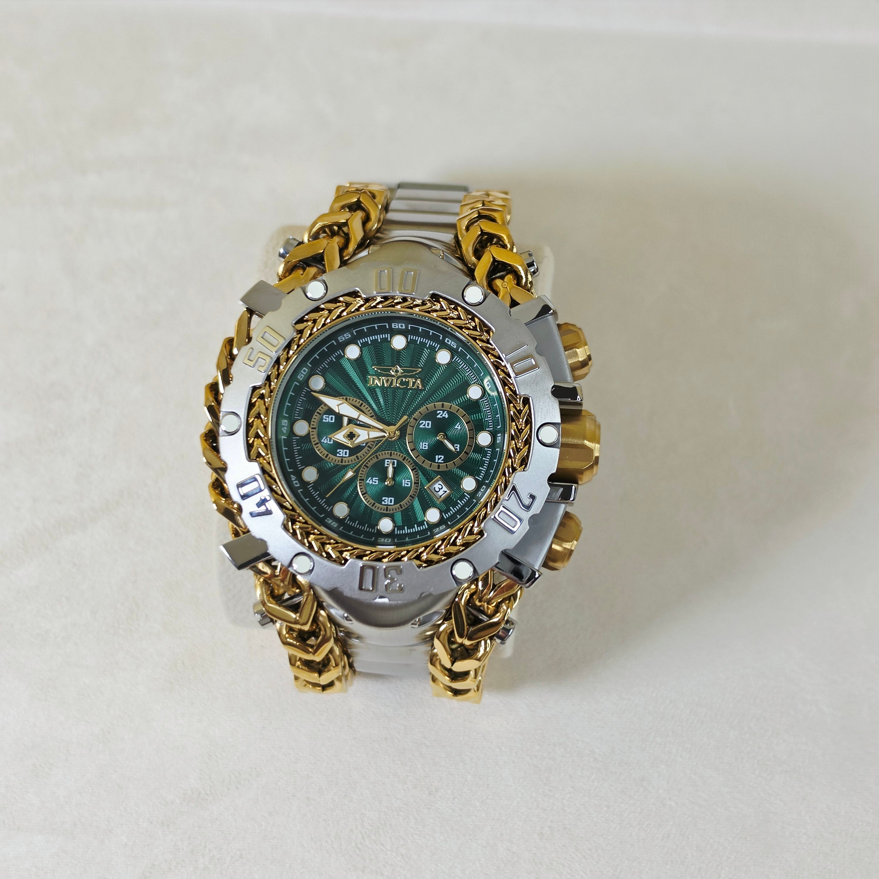 A luxury wristwatch by Invicta, featuring a green sunburst dial, a silver-tone bezel with Roman numerals, and a distinctive gold-tone chain-link bracelet, displayed on a light beige background.