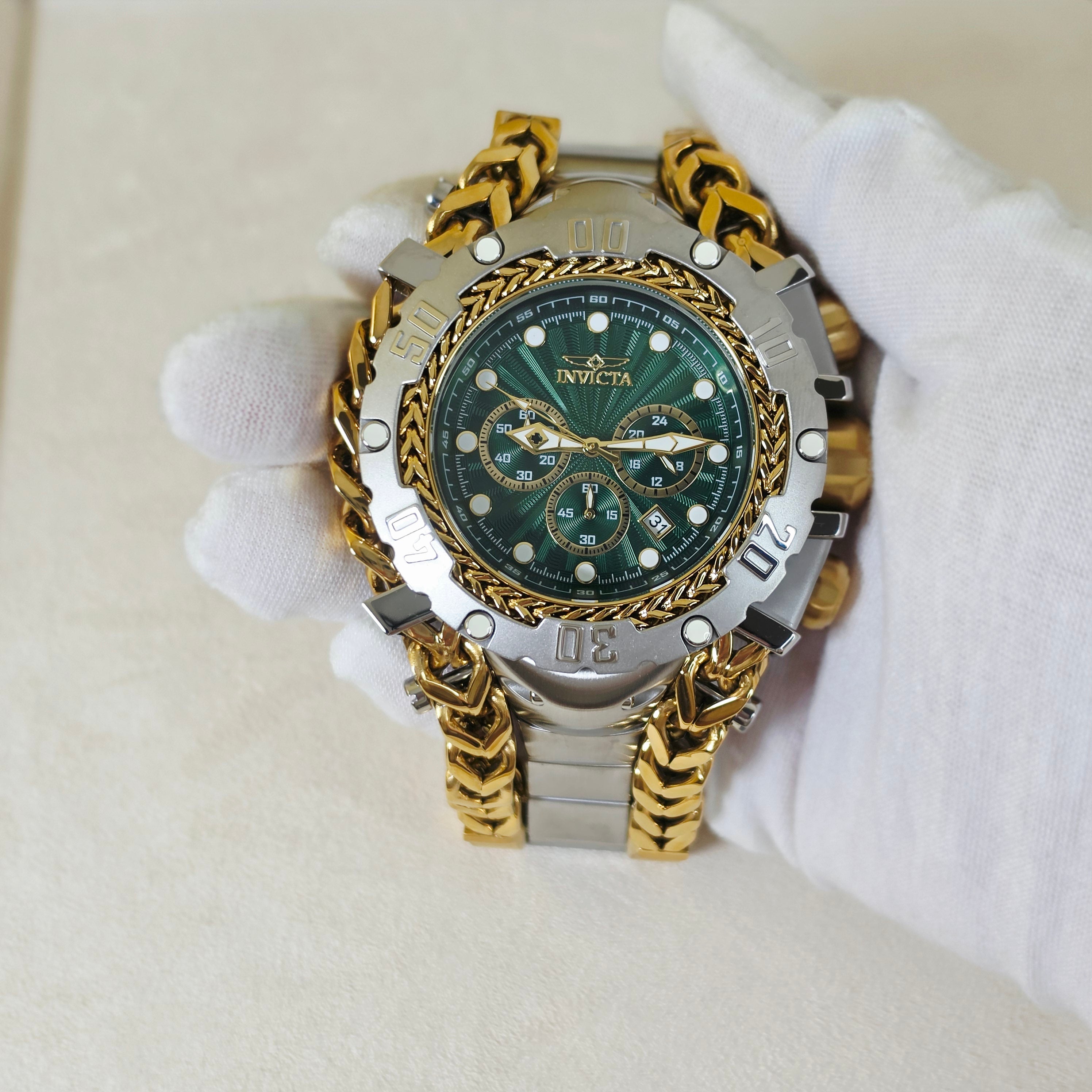 A heavy-duty Invicta wristwatch with a green dial, silver-toned case, and gold-toned chain link bracelet, held by a hand wearing a white glove.