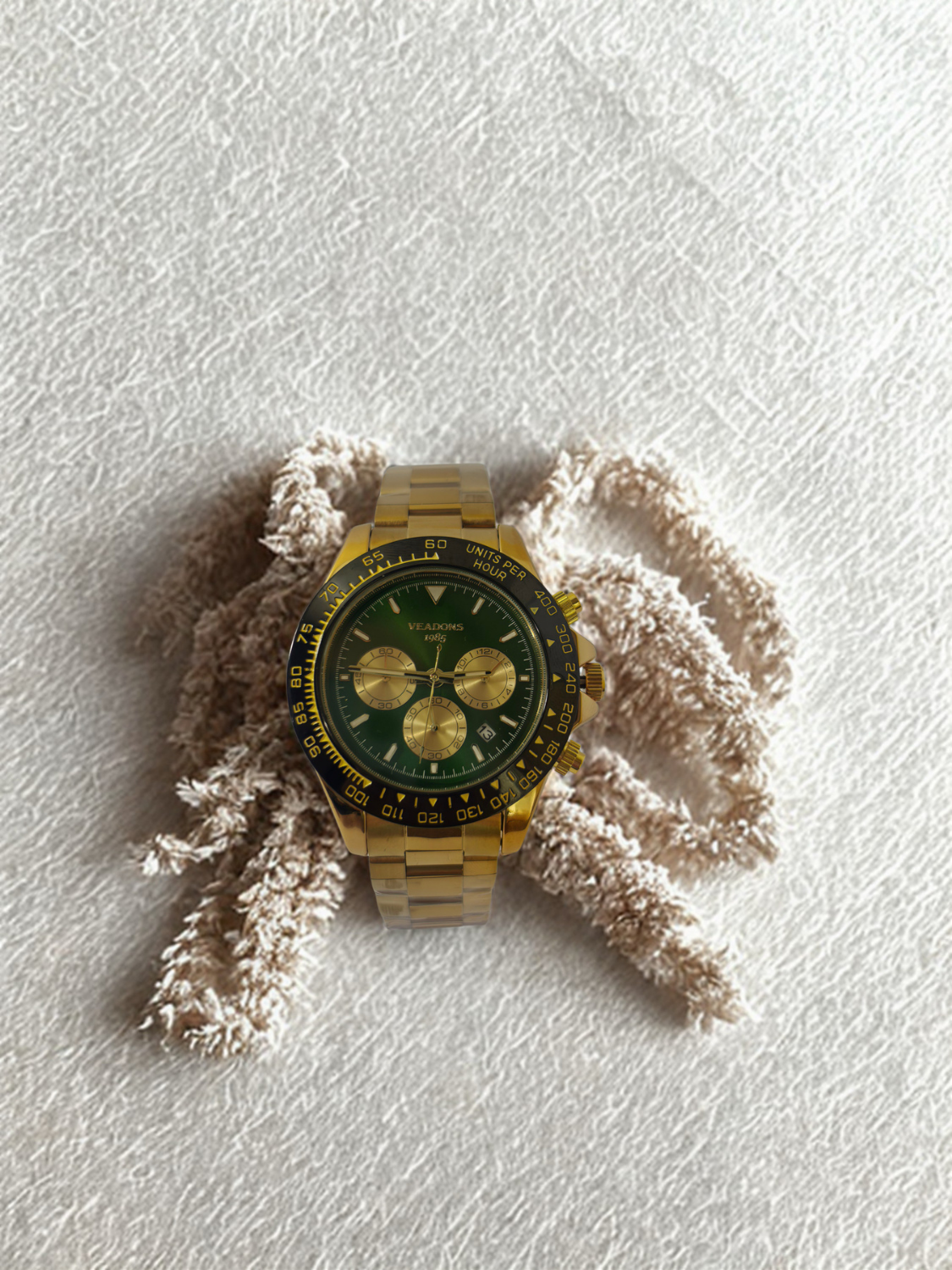 gold chronograph watch with green dial and tachymeter bezel
