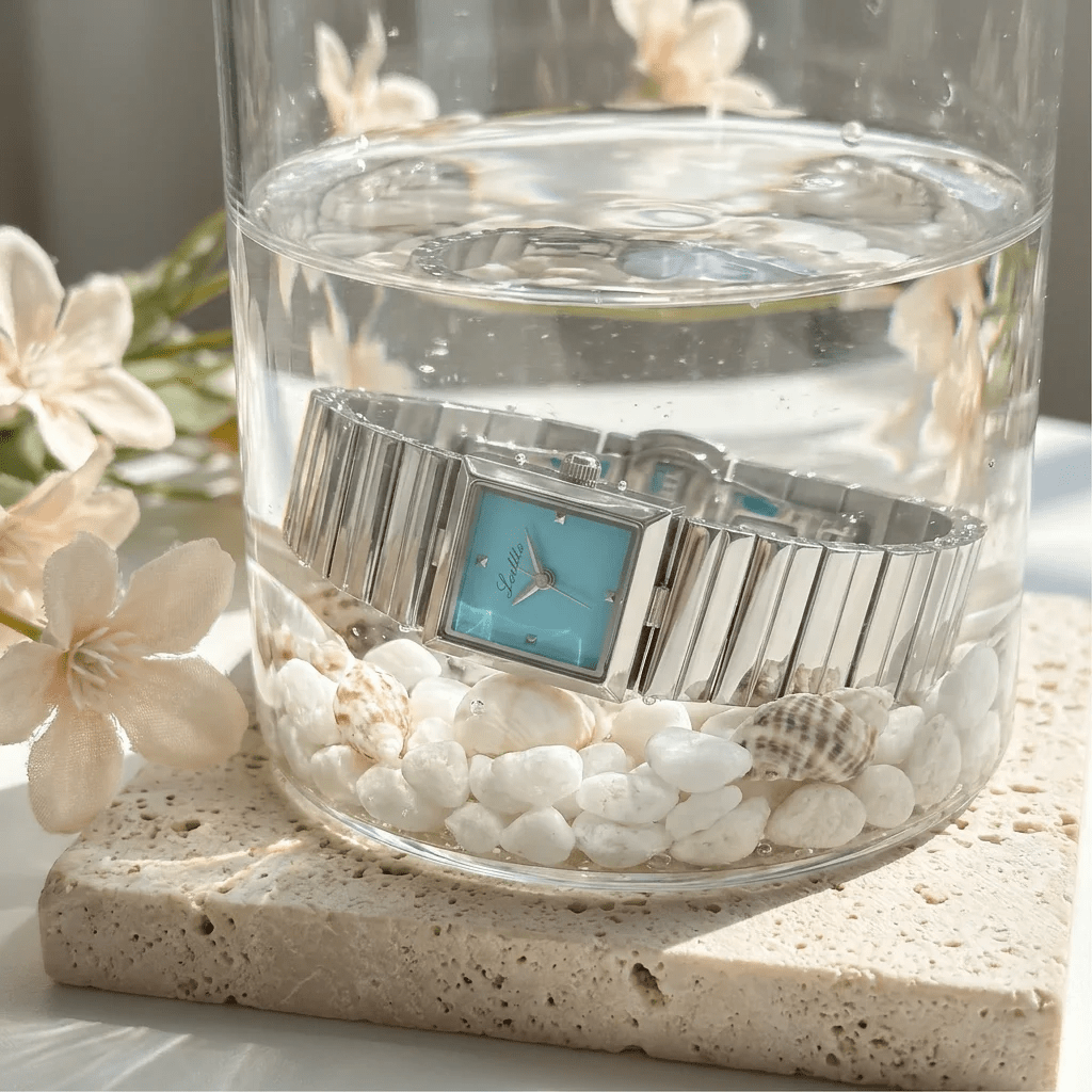 Turquoise dial square bracelet watch displayed in water with seashells

