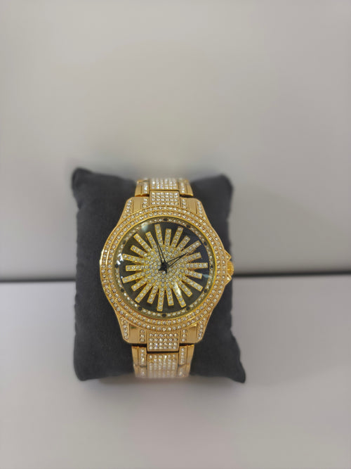 	Side view of gold-tone crystal pavé watch on dark pillow, crown detail