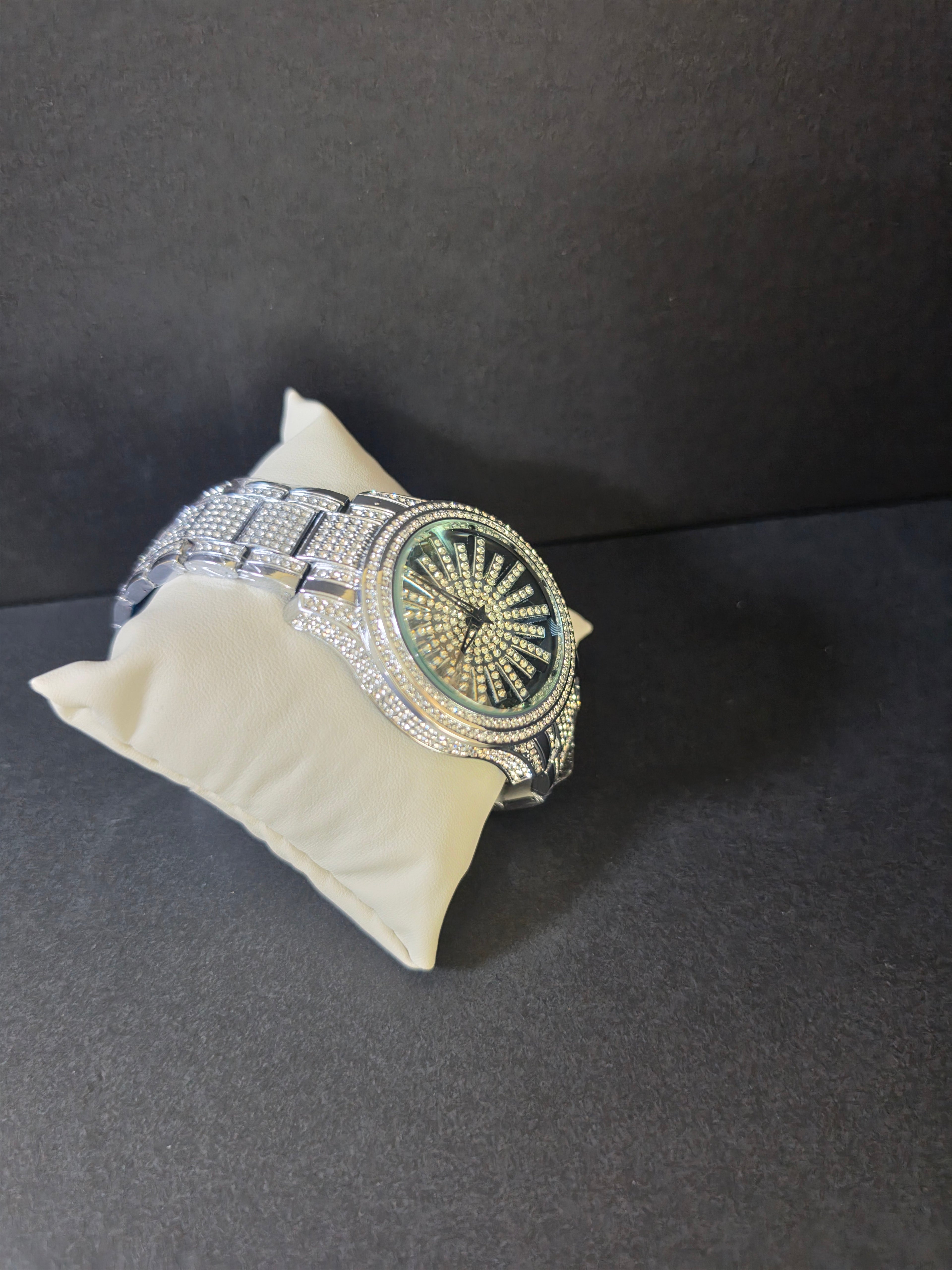 Side view of silver-tone crystal pavé watch bracelet against dark background